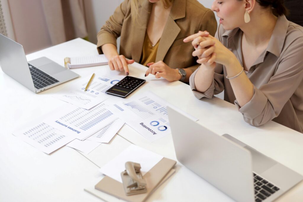 Two business professionals reviewing financial documents and using a calculator at a desk